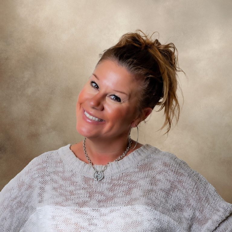 Charity For Charity Smiling woman with long hair, wearing a light sweater, against a neutral background.