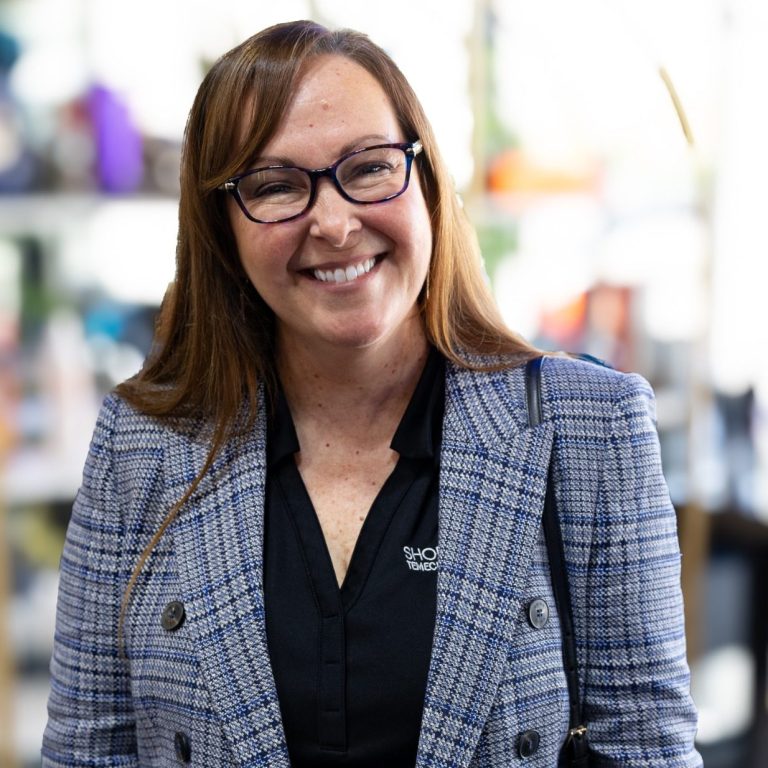 Temecula Valley Chamber of Commerce Smiling woman with long brown hair, wearing glasses and a plaid blazer.