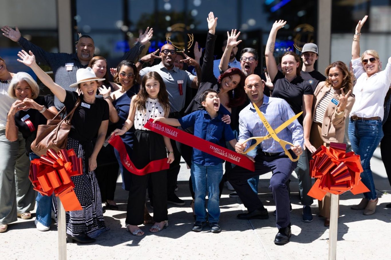 Business ribbon cutting photos A diverse group of people celebrating and posing with ribbons at a grand opening event.