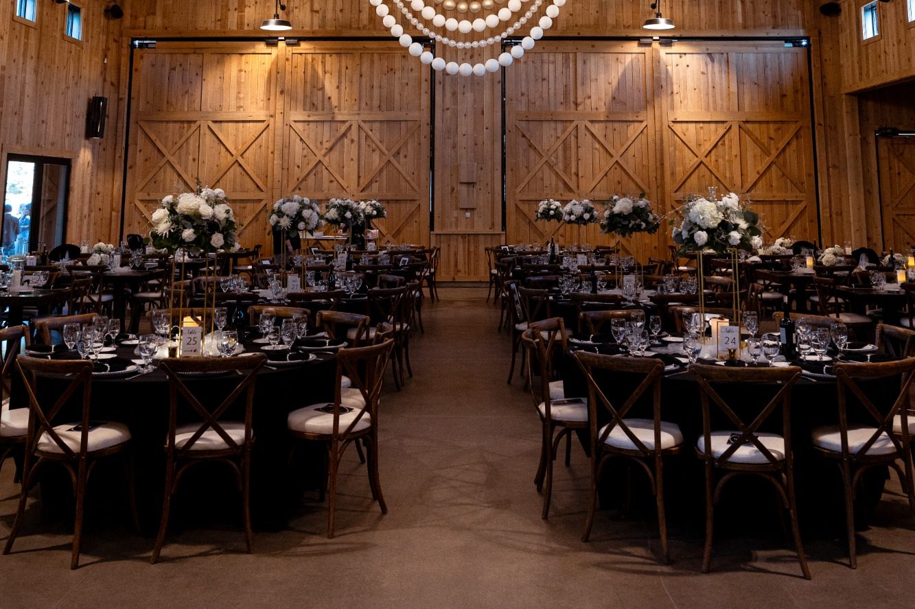 Event photos Elegant banquet setup in a wooden hall with round tables and floral centerpieces.