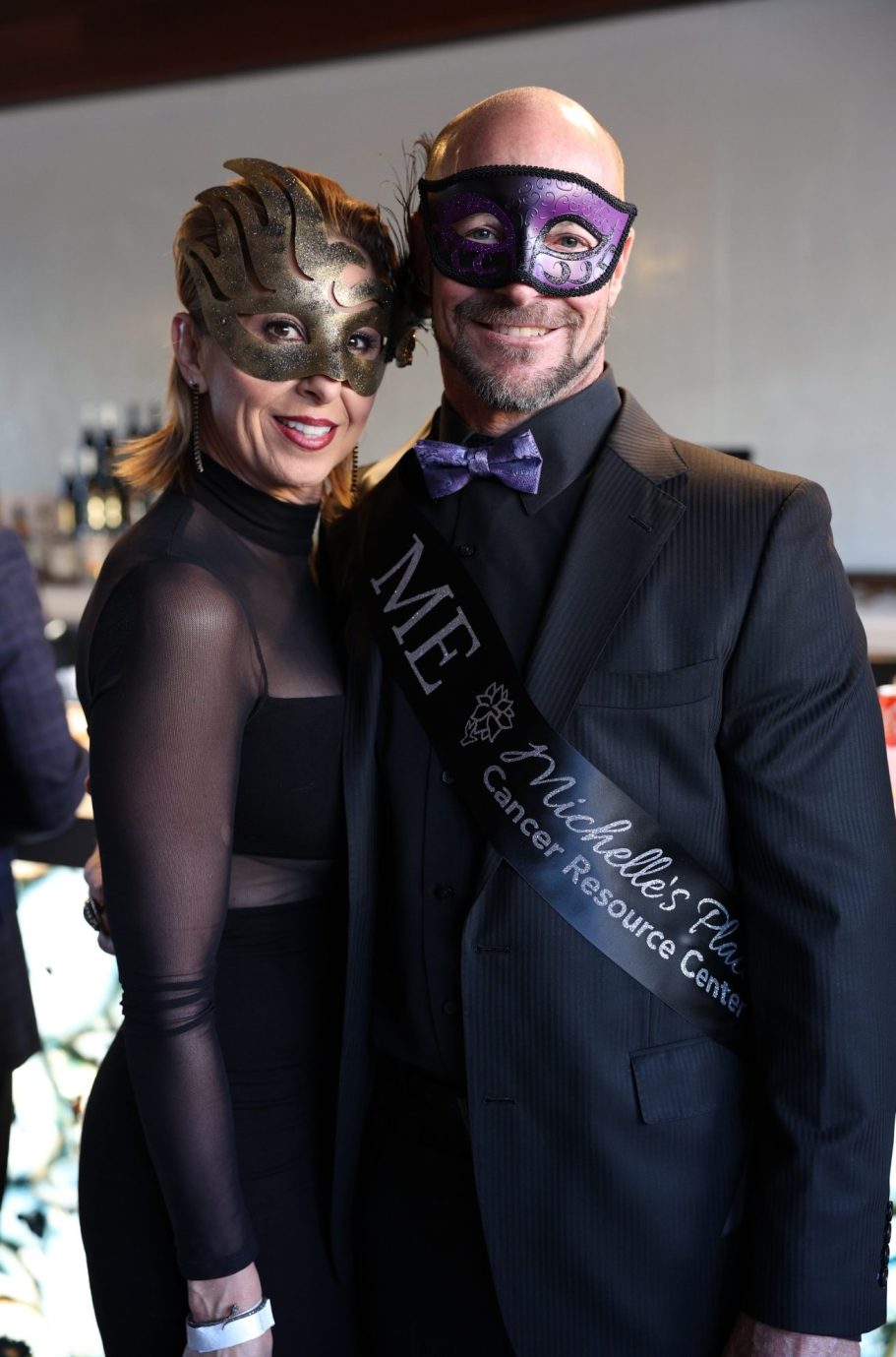 A couple in formal attire wearing masks, celebrating.
