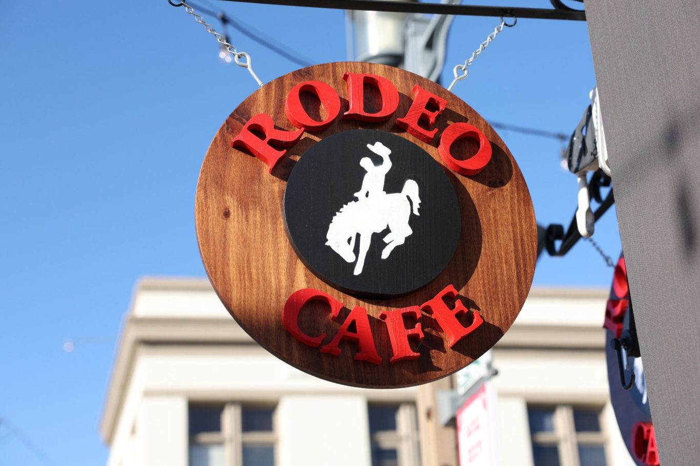 Promotional videos Sign for "Rodeo Café" featuring a cowboy on a horse against a blue sky.