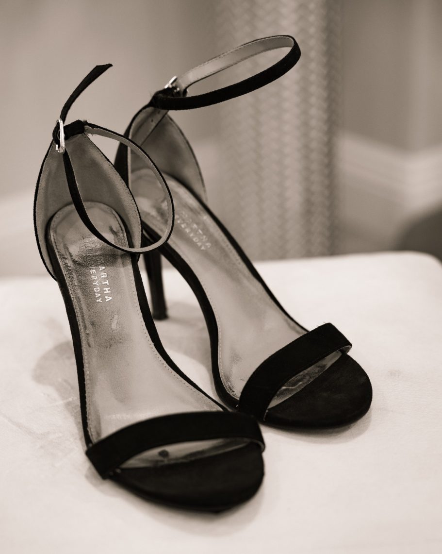 Black high-heeled sandals with ankle straps and a glossy finish.